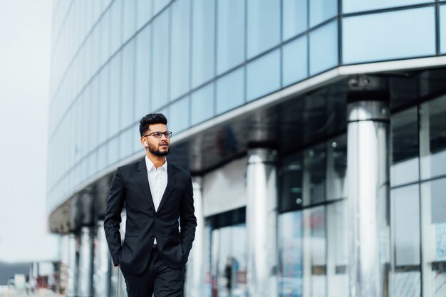 Een moderne Indiase man gaat naar een zakelijke bijeenkomst, achter hem een modern gebouw