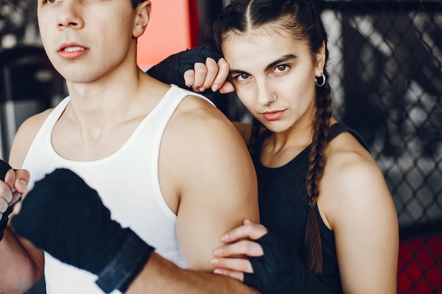 Een mooi en atletisch sportkledingmeisje dat in de gymnastiek met haar vriend opleidt