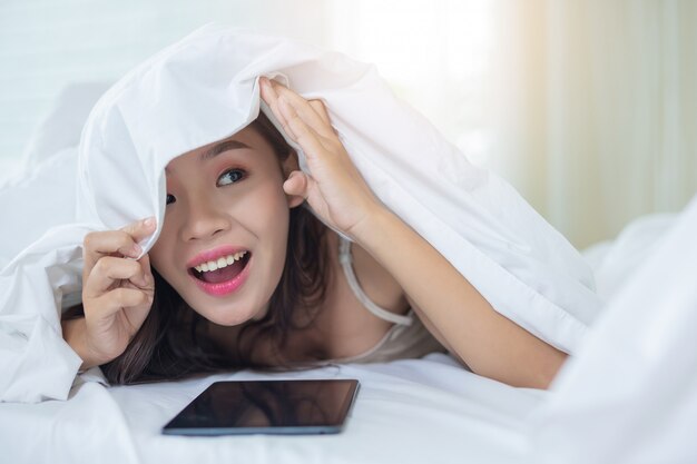 Een mooie Aziatische vrouw ontspant en werkt met een laptop, thuis lezen.