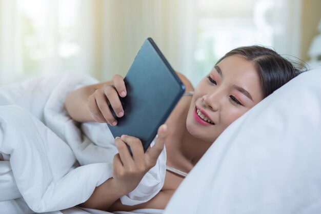 Een mooie Aziatische vrouw ontspant en werkt met een laptop, thuis lezen.