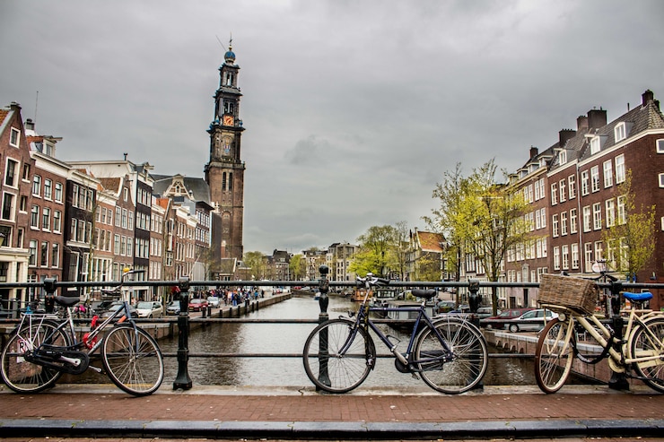 Gratis Foto een mooie foto van fietsen die weer op het hek leunden op een brug over de rivier.