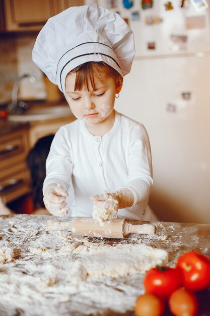 Een mooie jonge kleine dochter kookt thuis in de keuken