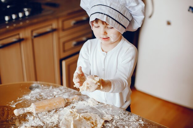 Een mooie jonge kleine dochter kookt thuis in de keuken