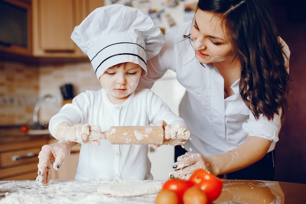 Een mooie jonge moeder met haar kleine dochter kookt thuis in de keuken