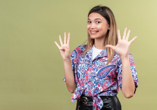 Een mooie jonge vrouw die een paisley-bedrukt overhemd draagt met nummer negen