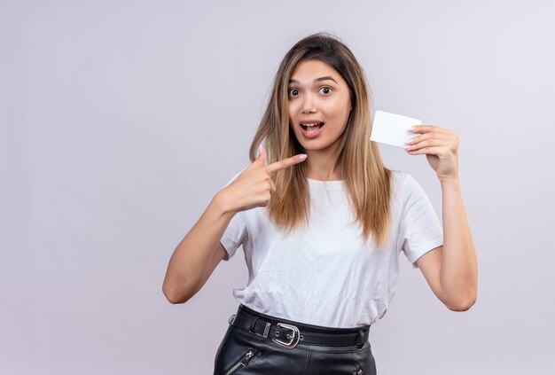 Een mooie jonge vrouw die in wit t-shirt op nota richt