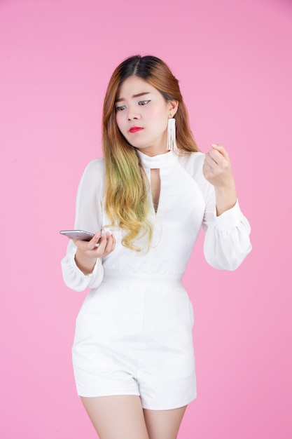 Een mooie vrouw gekleed met een witte jurk, die de telefoon en gezichtsemoties toont