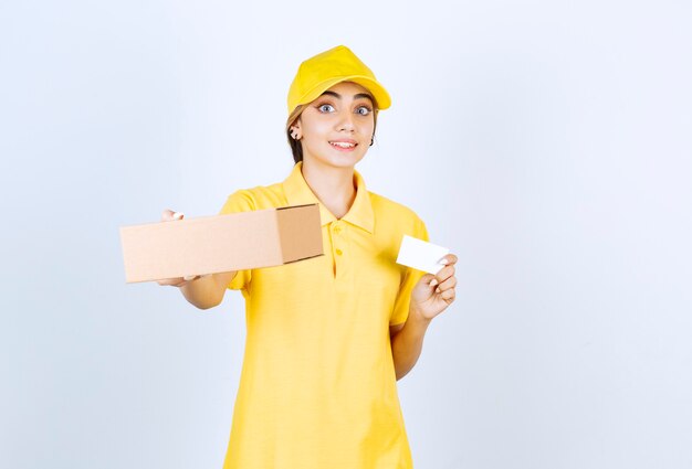 Een mooie vrouw in geel uniform met een bruine lege doos van ambachtelijk papier.