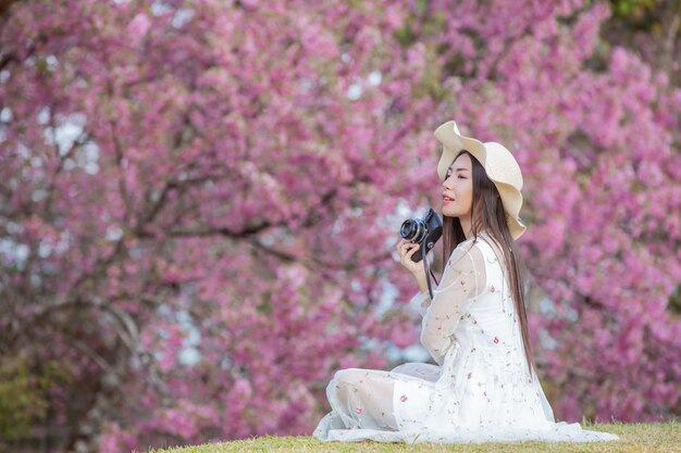 Een mooie vrouw maakt een foto met een filmcamera in de bloementuin van Sakura.