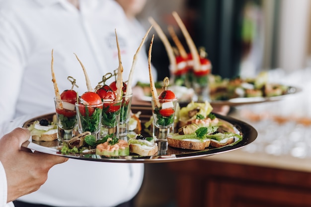 Gratis foto een ober houdt een presenteerblad met snacks