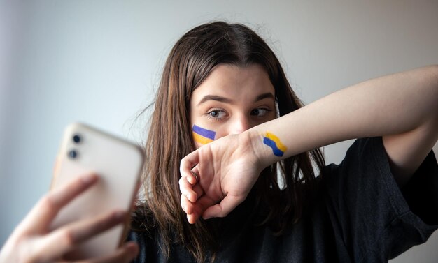 Een Oekraïens meisje met een geschilderde vlag van Oekraïne op haar gezicht maakt een selfie