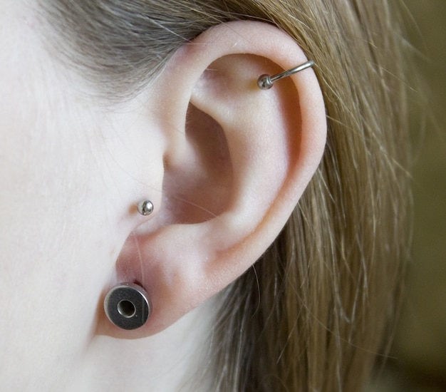 Een oor met een tunnel en oorbellen piercing