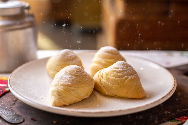 Een oostelijke schatje van vooraanzichtbadambura met zoete okkernoten binnen het witte poeder van de plaatsuiker binnen het gebakjebakkerij van het witte plaatkoekje