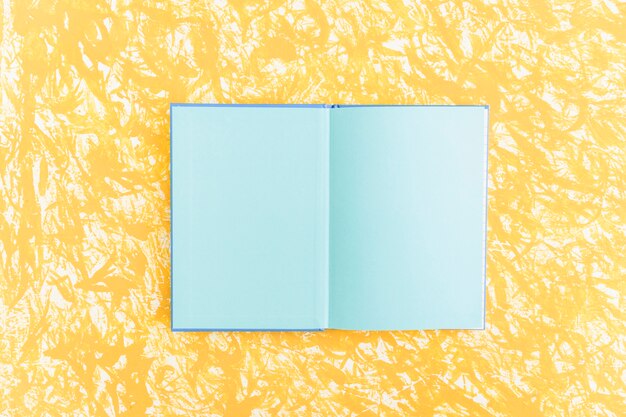 Een open blauw pagina notitieboek op gele geweven achtergrond