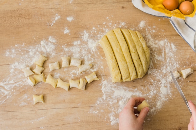 Gratis foto een opgeheven mening van een persoon die de eigengemaakte italiaanse deegwarengnocchi voorbereidt