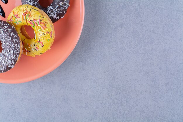 Een oranje bord heerlijke chocolade donuts met hagelslag.