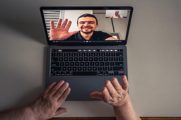 Een oude vrouw communiceert met haar zoon via een videoverbinding via een laptop