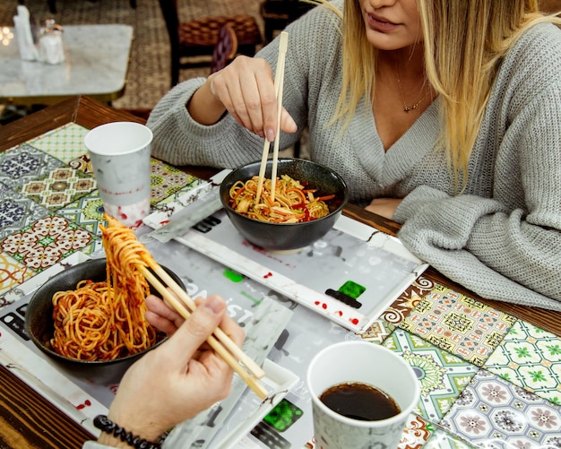 Gratis foto een paar dat tomatenspaghetti met stokken eet