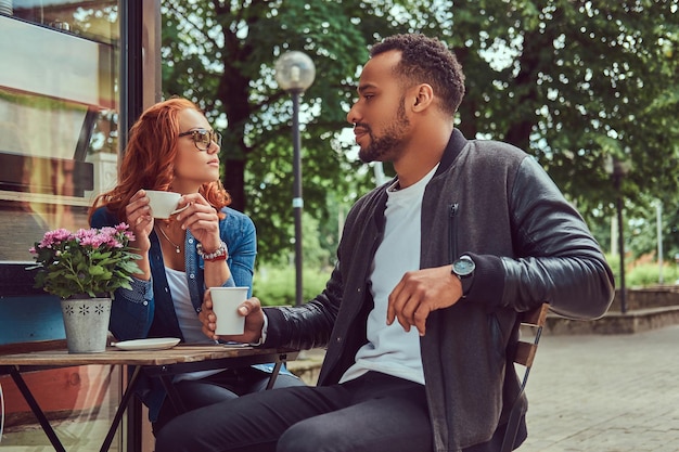 Een paar dating drinkt koffie, zittend in de buurt van de coffeeshop. Buiten op een date.