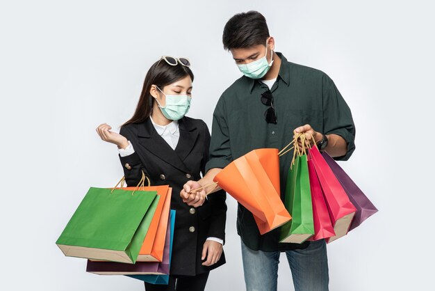 Een paar mannen en vrouwen droegen maskers en droegen veel papieren zakken om te winkelen