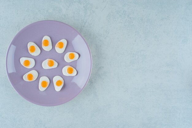 Een paars bord met zoete gelei-snoepjes roerei op een witte ondergrond