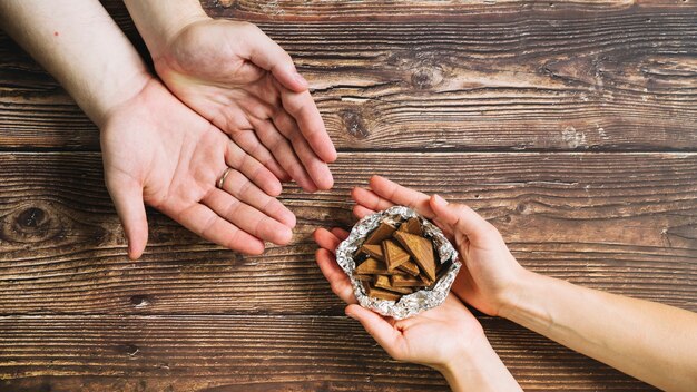 Gratis foto een persoon die chocoladestukjes in de folie op houten achtergrond