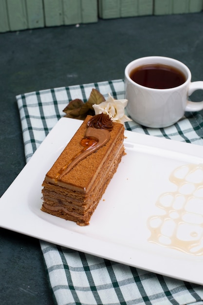 Een plak cake met karamelsaus en een kopje thee