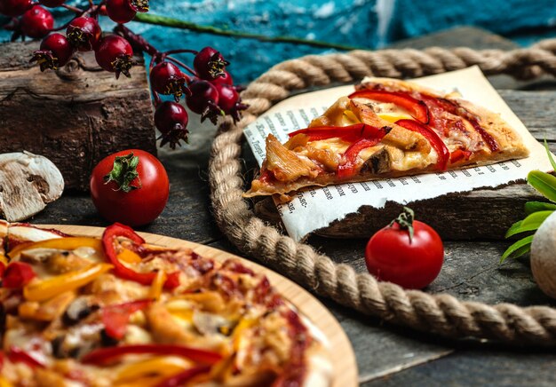 Een plak pizza en tomaten op tafel