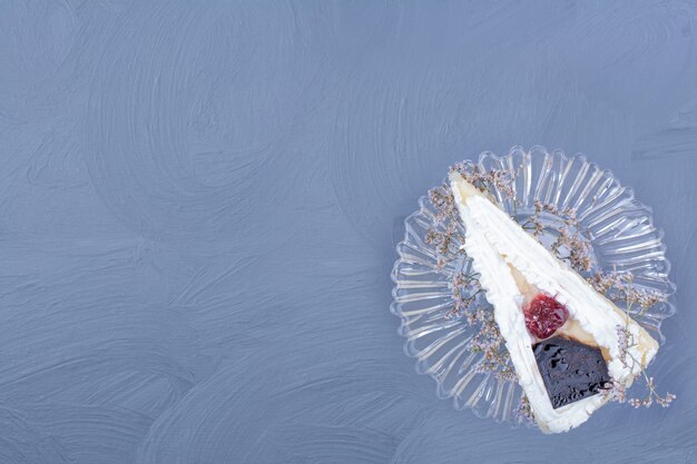 Een plak van cheesecake in een glazen schotel op blauwe achtergrond