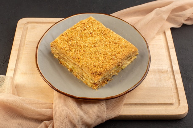 Een plak van de vooraanzichttaart lekker en gebakken binnenplaat op het houten bureau en het donkere suikergoed van het cakekoekje