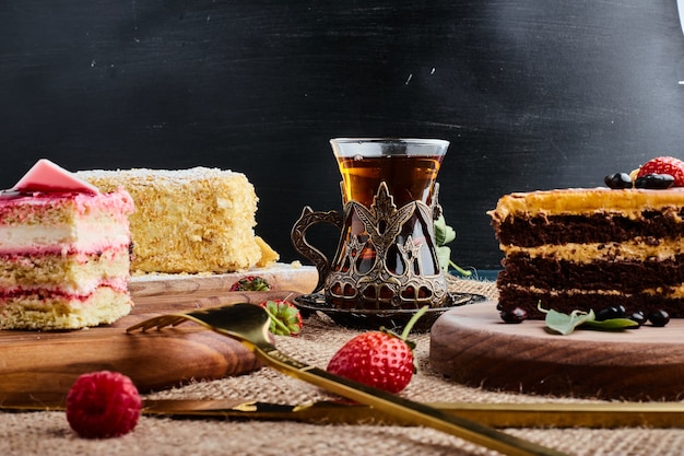 Een plakje chocoladetaart op een houten bord met een glas thee.