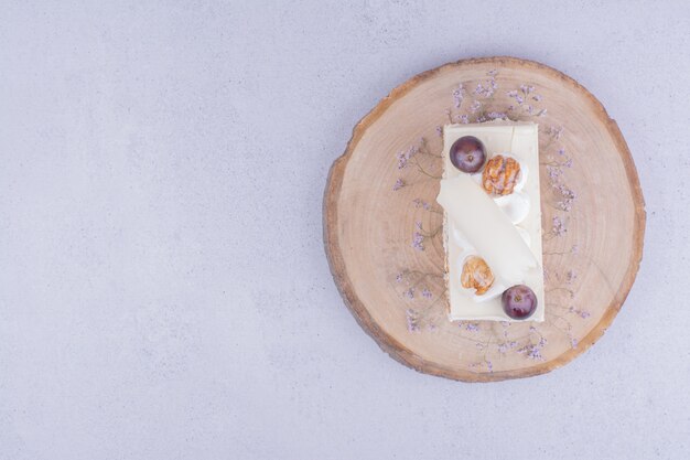 Een plakje kokoscake met druivenmost en walnoot op een houten bord