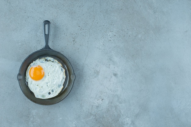 Een portie gebakken ei in een pan op marmeren achtergrond. Hoge kwaliteit foto