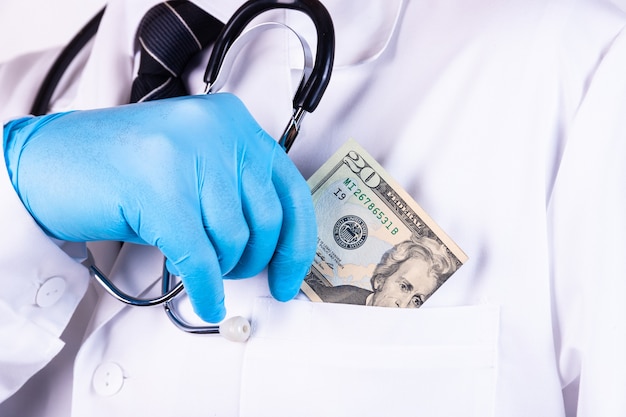 Een portret van een mannelijke arts met geld in zijn zak op wit wordt geïsoleerd