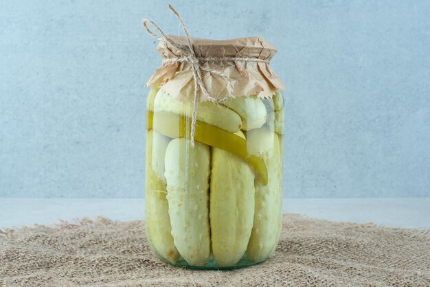 Een pot zelfgemaakte ingelegde komkommers op jute.
