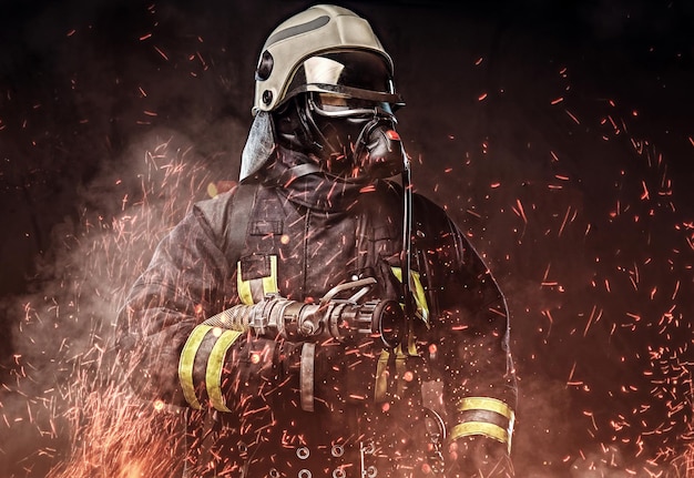 Een professionele brandweerman gekleed in uniform en een zuurstofmasker staande in vuurvonken en rook op een donkere achtergrond.