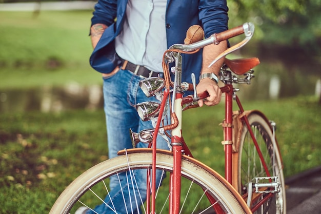 Een reiziger gekleed in vrijetijdskleding met een rugzak, ontspannen in een stadspark na het rijden op een retro fiets.