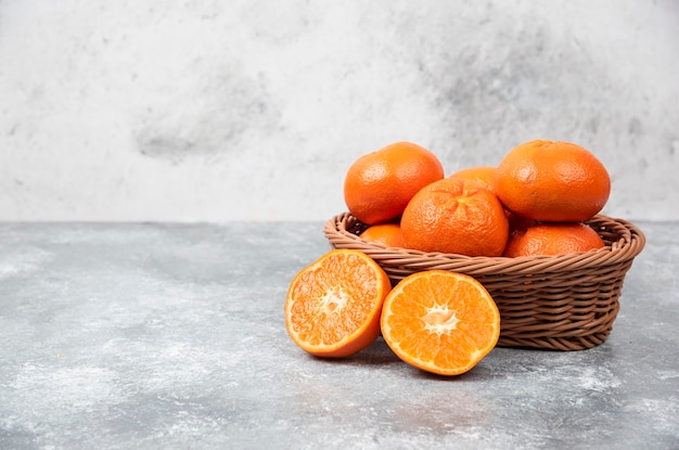 Een rieten doos vol sappig oranje fruit op stenen tafel.