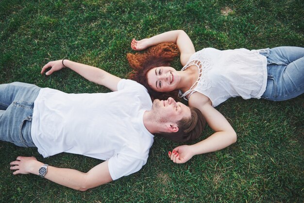 Een romantisch paar jonge mensen die op het gras in het park liggen.