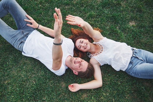 Gratis foto een romantisch paar jonge mensen die op het gras in het park liggen.