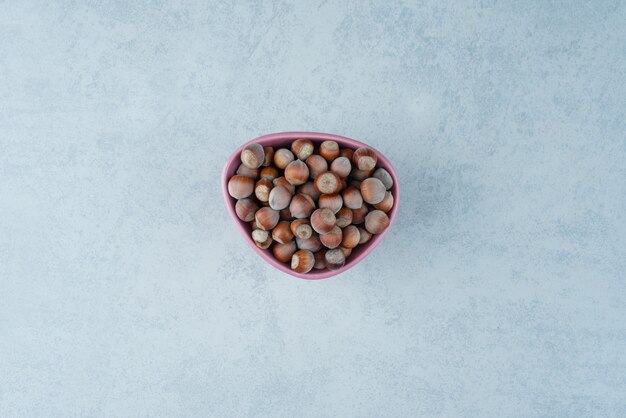 Een roze bordje vol noten op marmeren achtergrond. Hoge kwaliteit foto