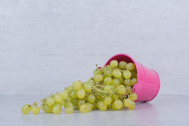 Een roze emmer vol groene zoete druiven. hoge kwaliteit foto