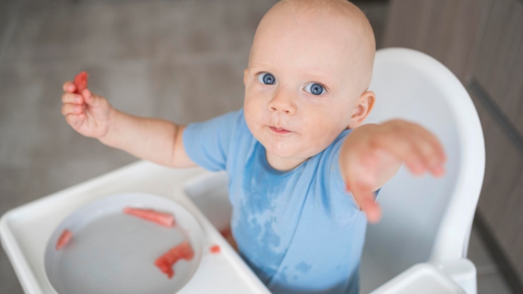 Gratis Foto een schattige baby die met eten speelt.