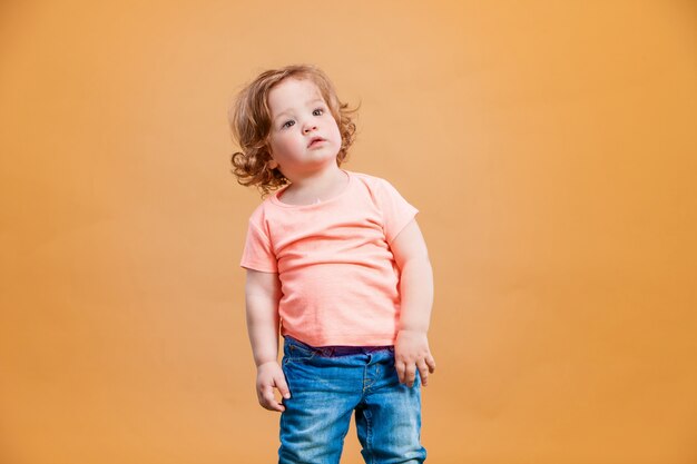 Een schattige baby meisje op oranje muur