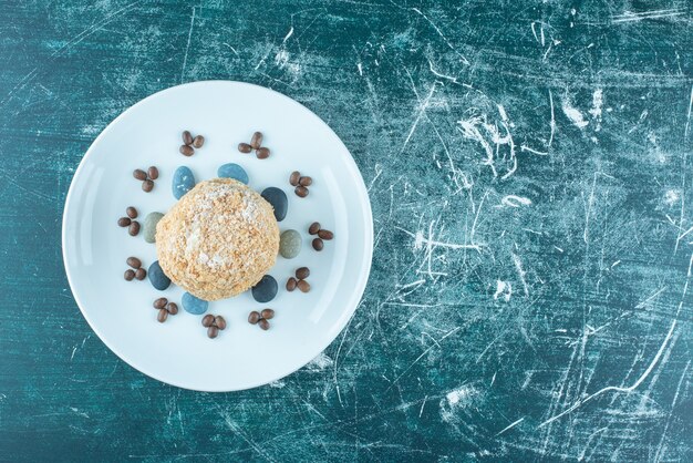 Een schotel met eekhoorncake, snoeprotsen en koffiebonen op blauw.