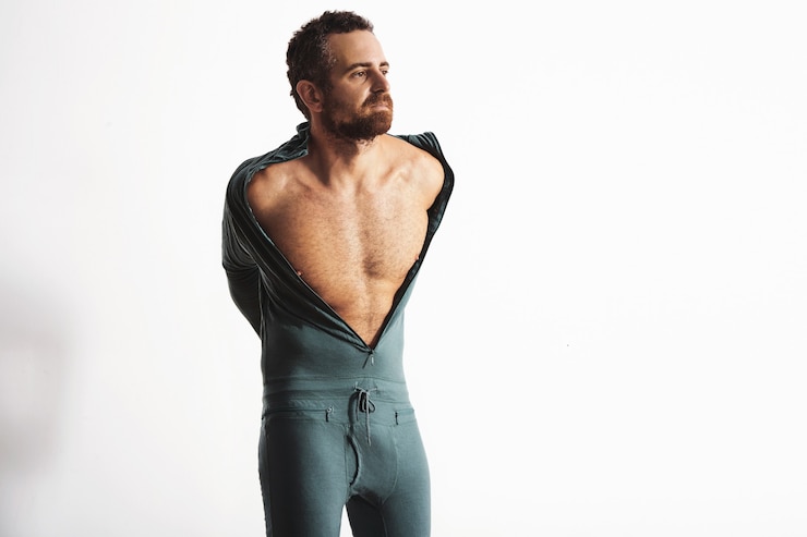Gratis Foto een serieuze en getailleerde, bebaarde mannelijke atleet die zijn warme winter snowboard baselayer thermosuit kleedt van merinowol