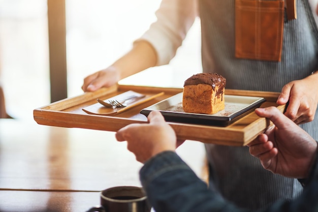 Een serveerster die een stuk chouxroom vasthoudt en serveert aan de klant in café