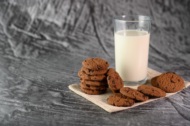 Een stapel koekjes en een glas melk op een doek op een houten tafel