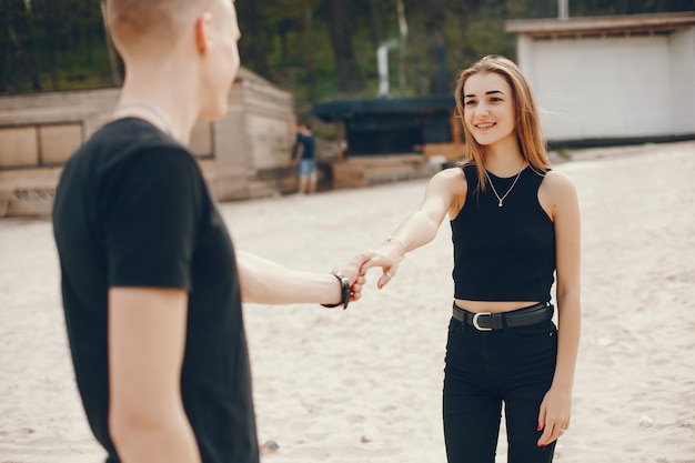 Een stijlvol en mooi paar in zwarte kleding brengt een goede tijd op het strand door