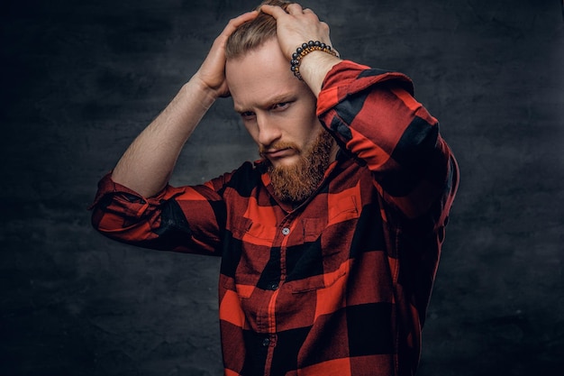 Een stijlvolle, bebaarde roodharige man gekleed in een rood fleece-shirt.